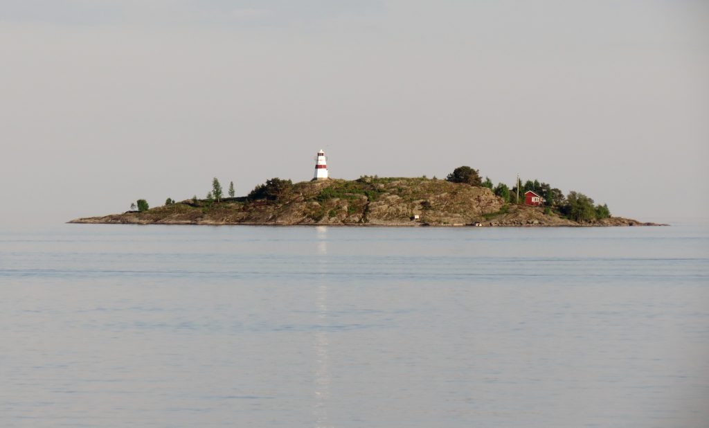 Fogdens fyr på en klippö i Vänern utanför Åmål, med blankt vatten en försommarkväll