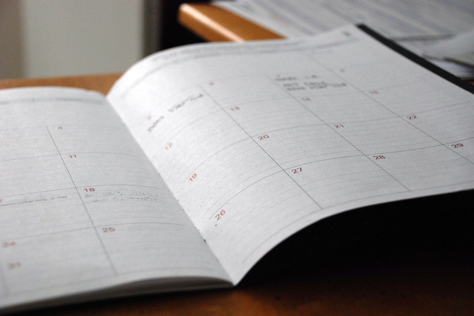 Uppslagen månadskalender på ett träskrivbord