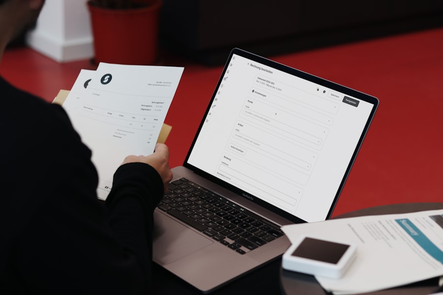 Person med pappersfakturor framför en laptop med ett digitalt formulär