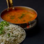 Krämig vegansk dal i kopparkärl med en skål basmatiris