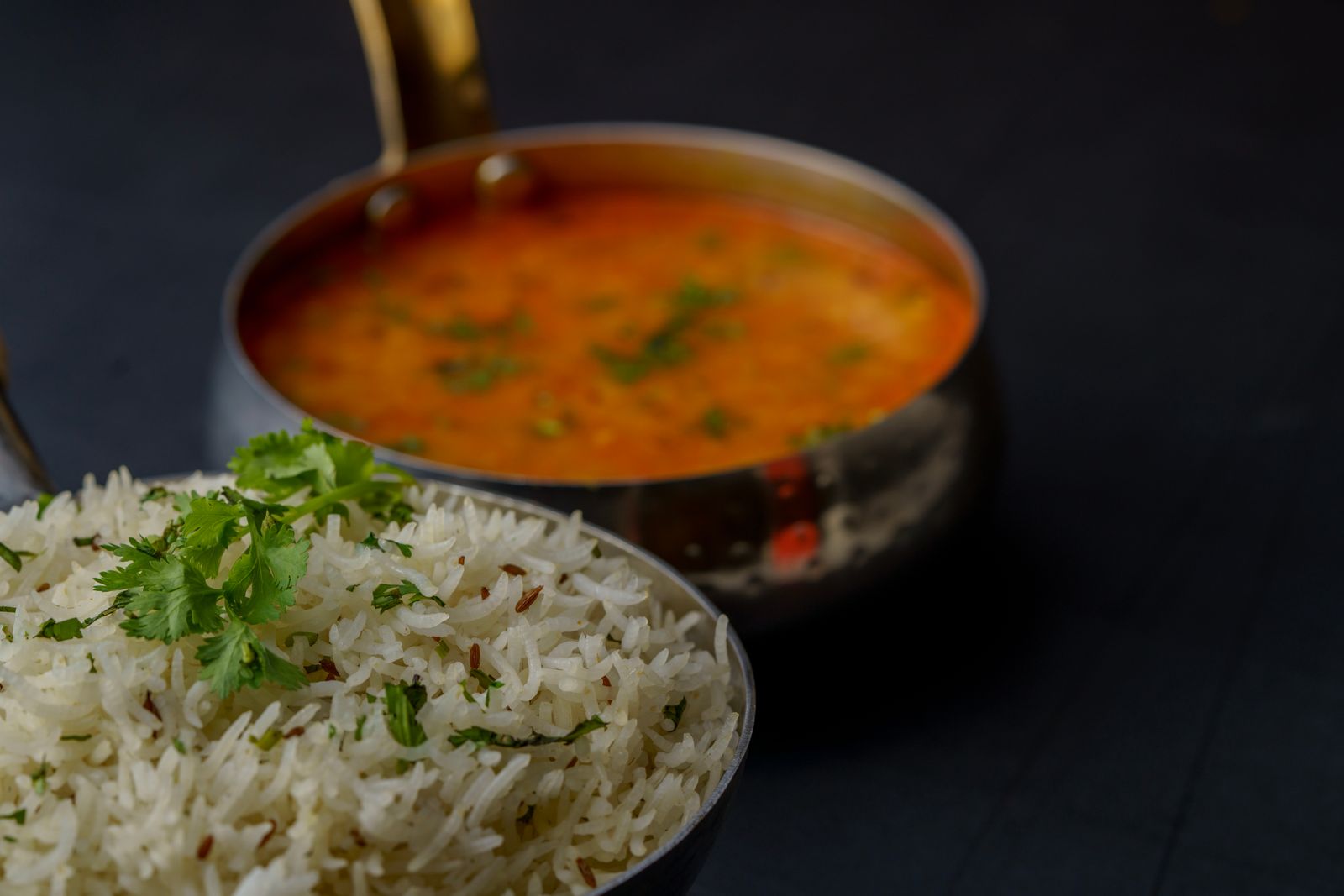 Krämig vegansk dal i kopparkärl med en skål basmatiris