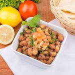 Skål med bönsallad toppad med tomat och örter