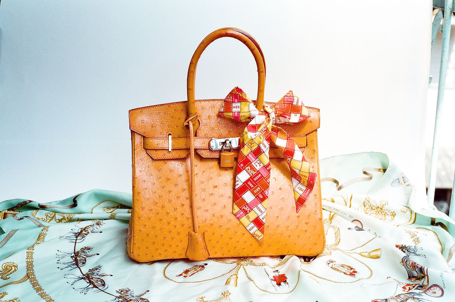 Hermès Birkin i strutsskinn med guldfärgade beslag, dekorerad med en Hermès-sjal på handtaget