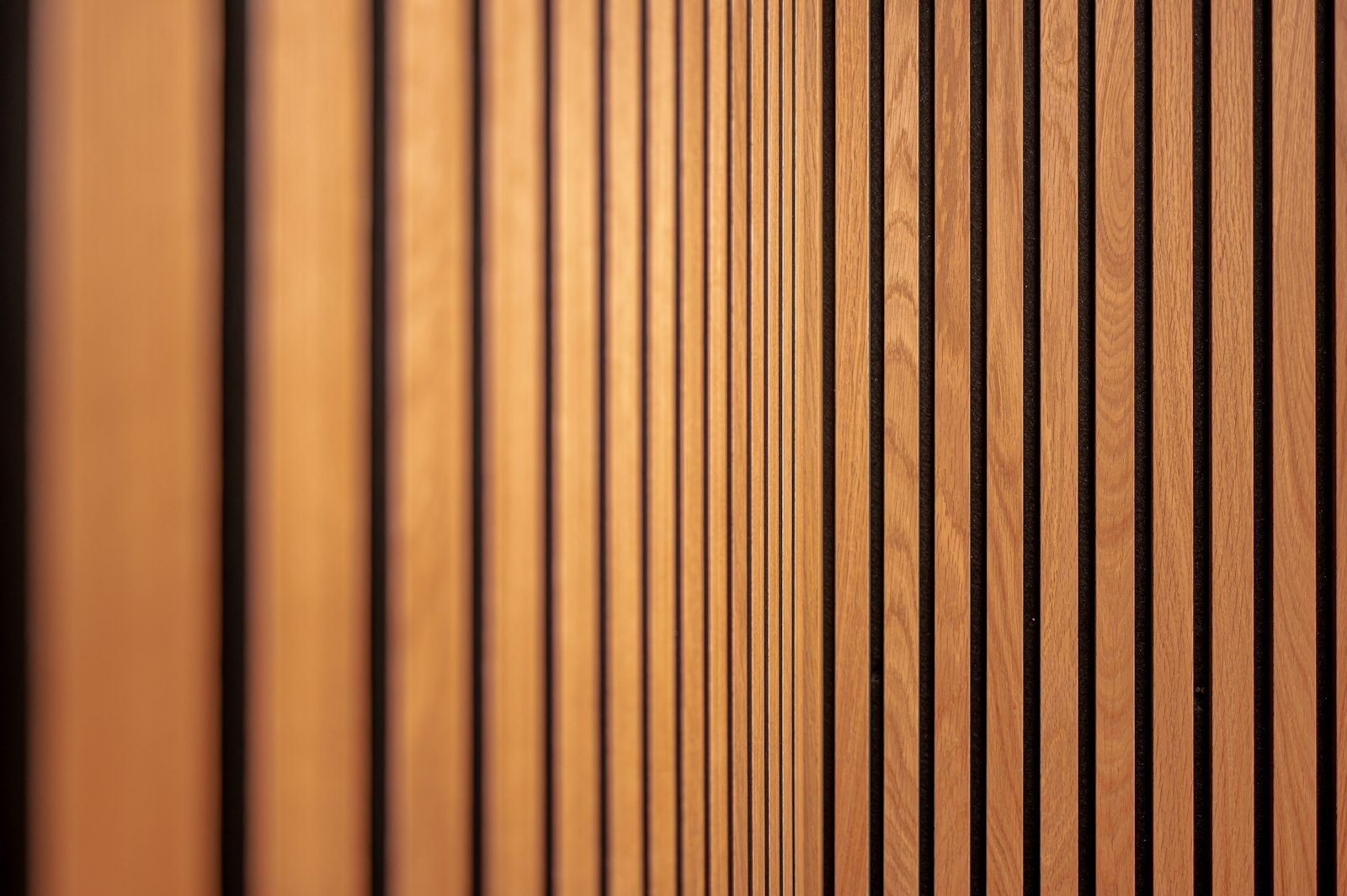 Närbild av akustikpanel med lodräta ekribbor och svart filt