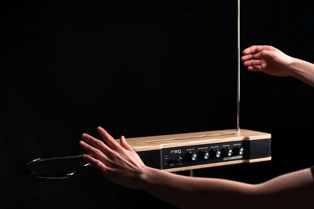 Moog Etherwave Theremin i asklada med svart frontpanel, spelad med en hand vid den lodräta tonantennen och en över volymslingan