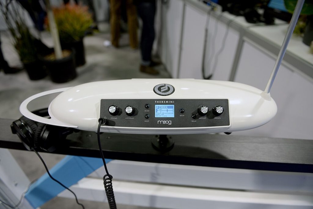 Vit Moog Theremini med högtalargallret synligt på ovansidan och ett par hörlurar inkopplade i frontpanelens hörlursuttag