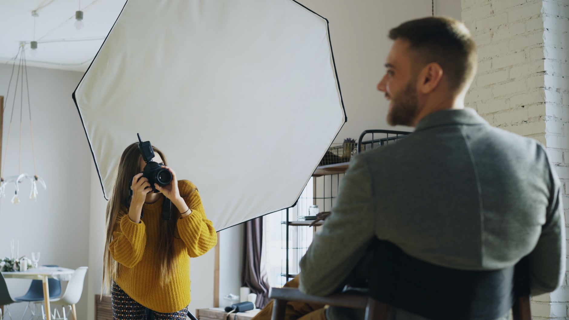 Fotograf tar porträtt av en man i kavaj i en ljus studio