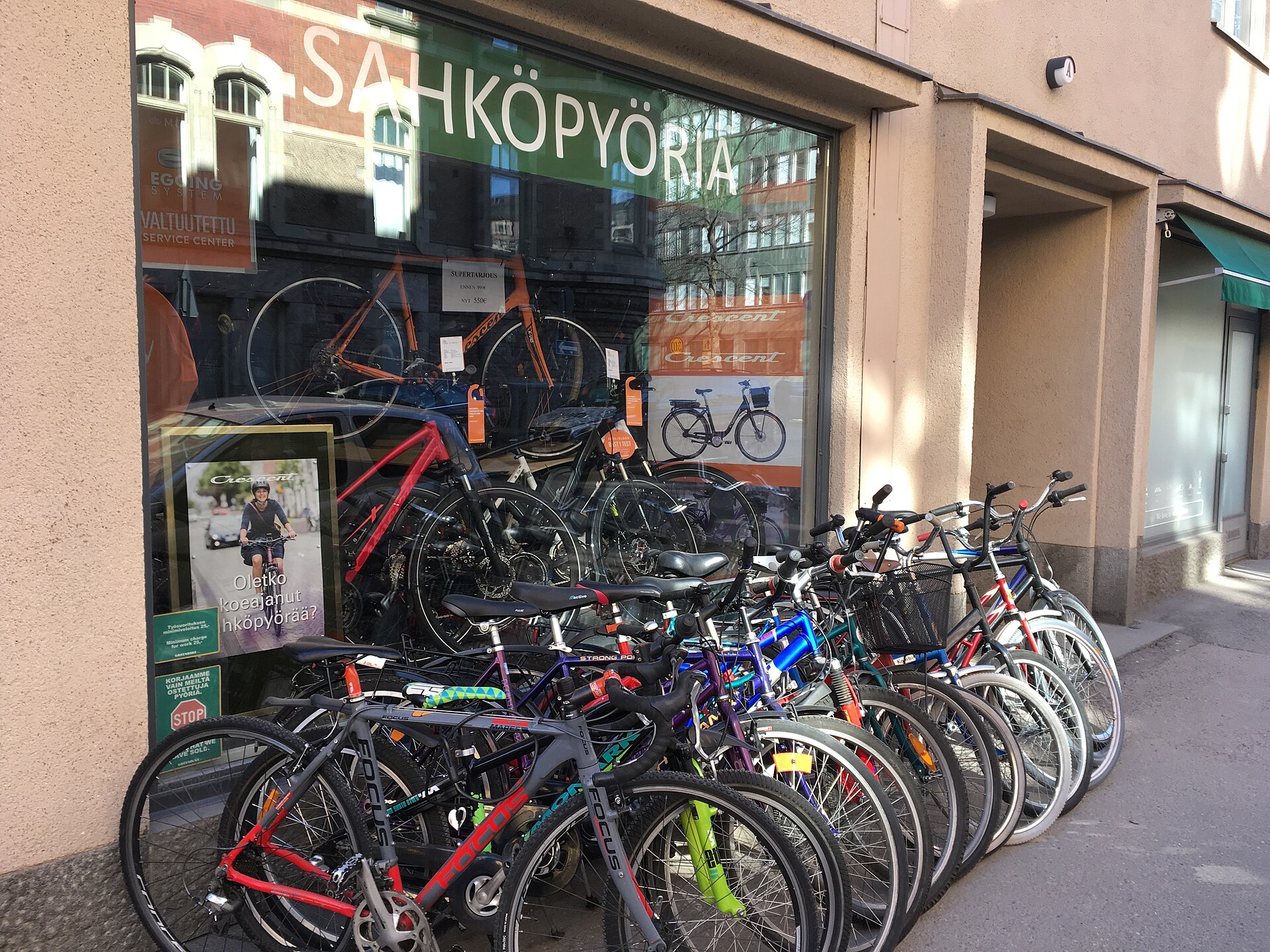 Cykelaffär med skylten Sähköpyöriä, finska för elcyklar, och en rad cyklar parkerade framför skyltfönstret