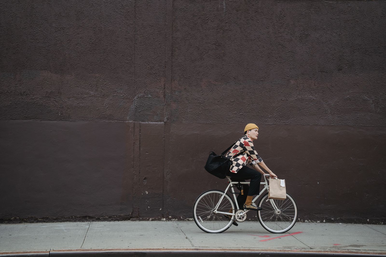 Cyklist på enväxlad cykel som rullar förbi en mörk vägg i staden