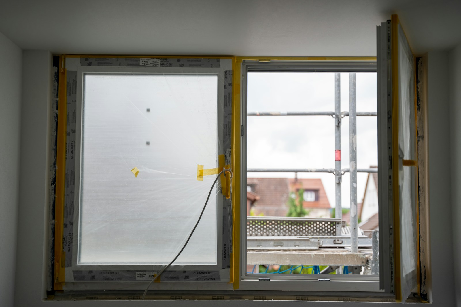 Ett nytt energieffektivt fönster monteras i en bostad under renovering, med byggnadsställning synlig utanför