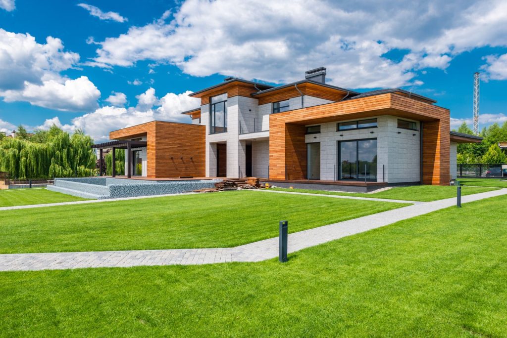 Modern villa med träfasad och grön gräsmatta en sommardag