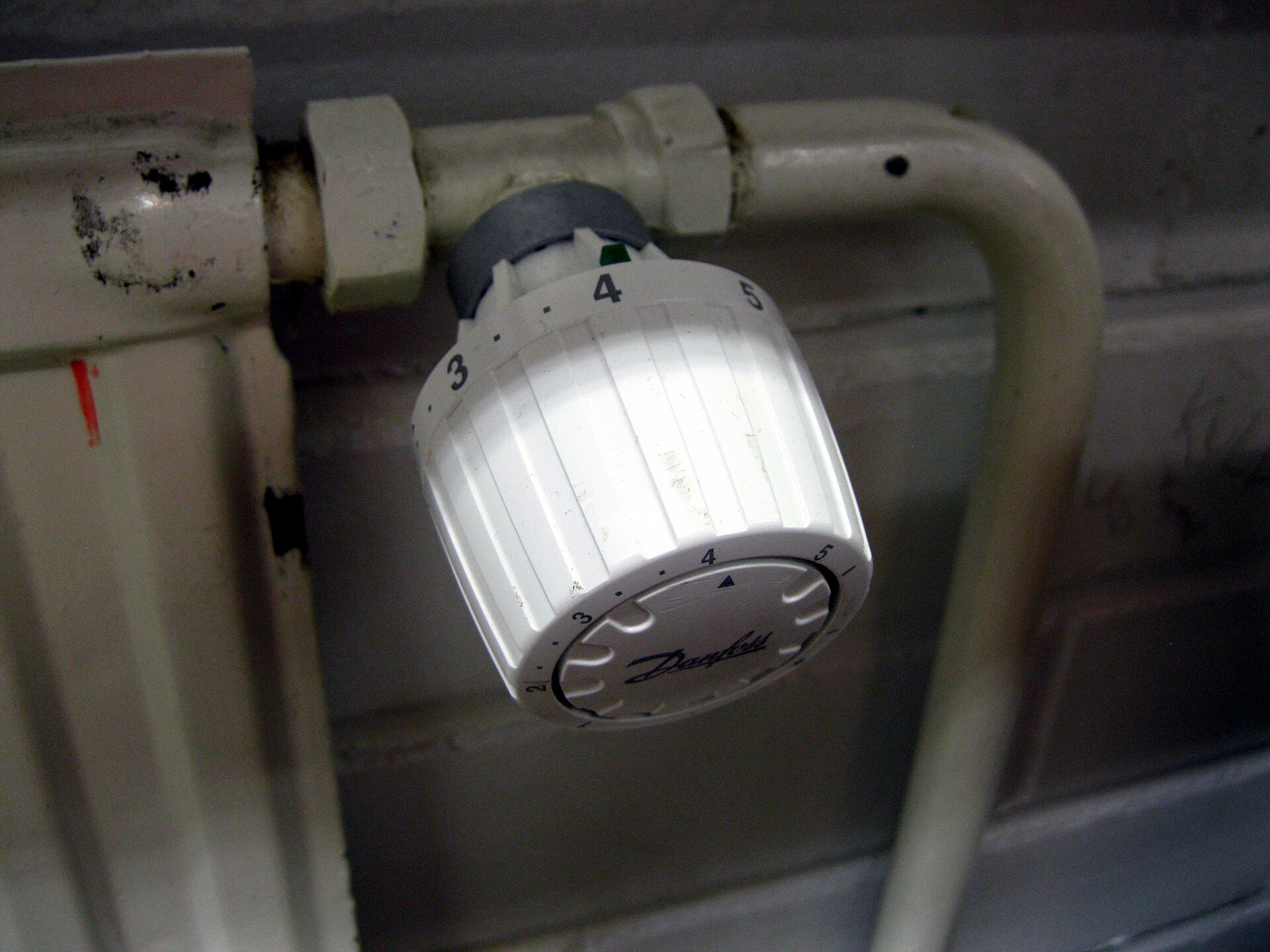 Närbild på en termostat monterad på en äldre radiator