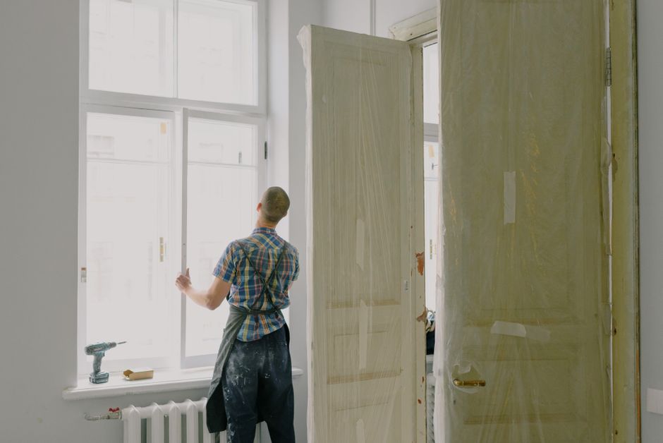 Hantverkare monterar ett nytt fönster i en ljus lägenhet under renovering