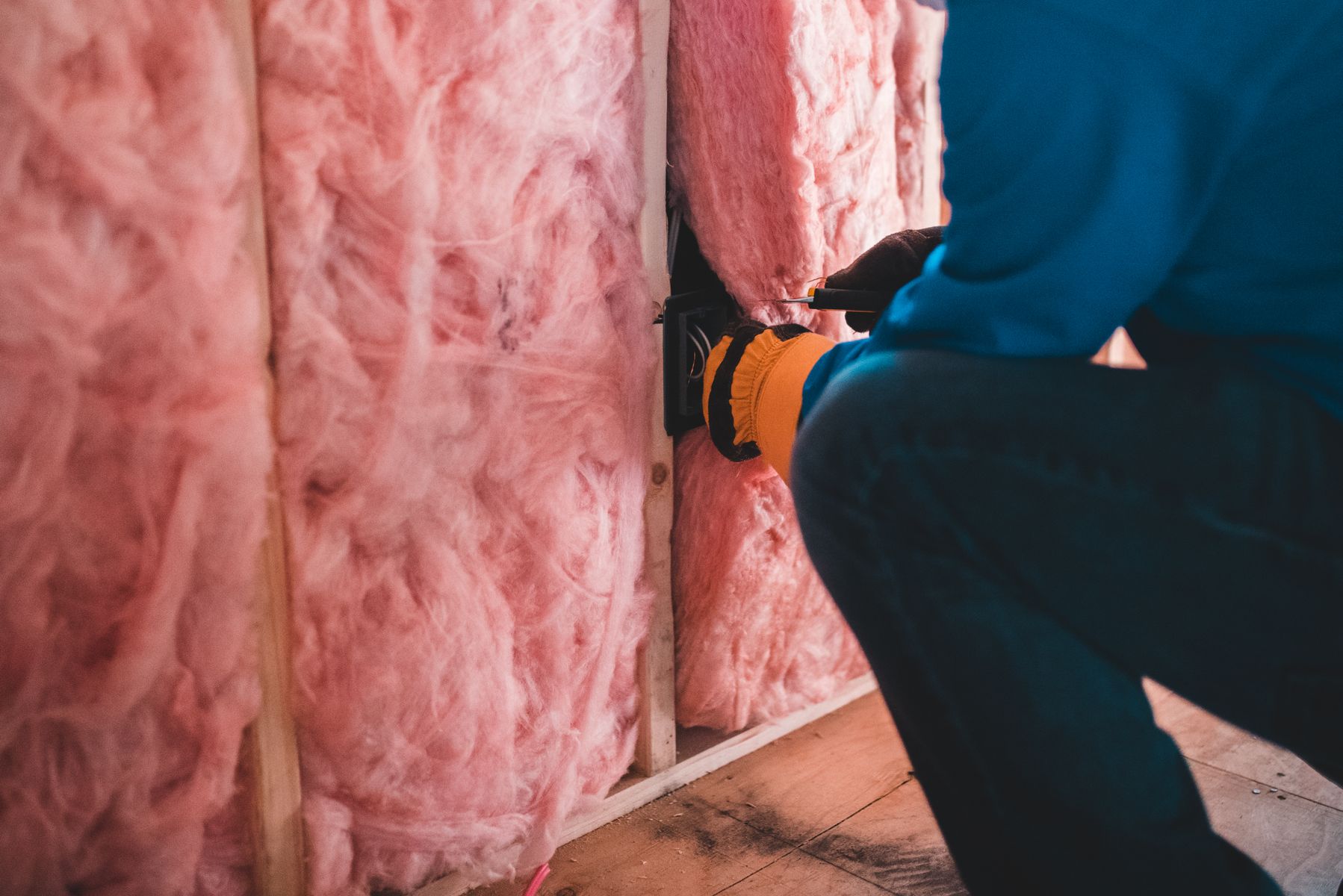 Hantverkare monterar rosa mineralull mellan reglar i en vägg