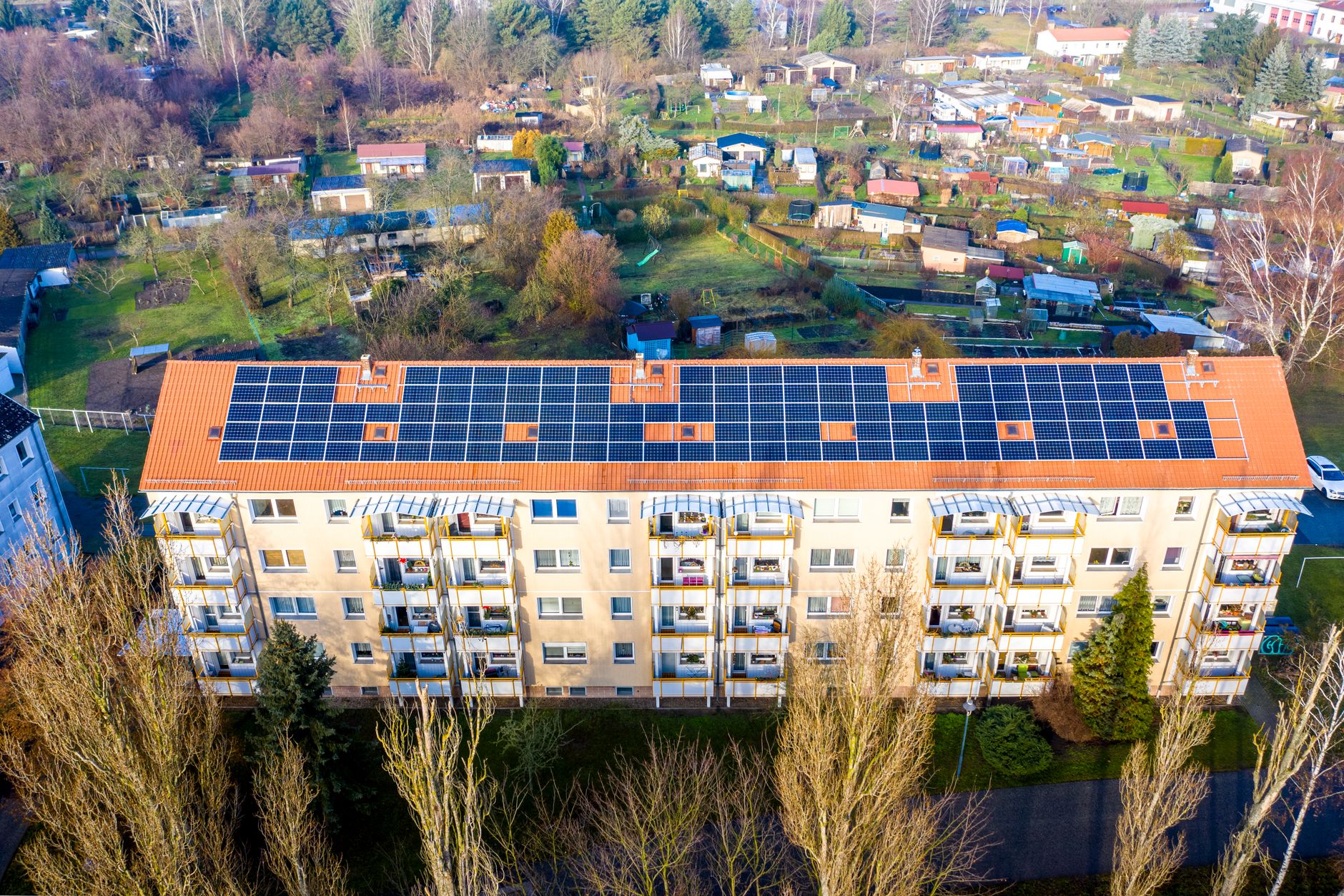 Flerbostadshus med solpaneler på det röda tegeltaket, sett från ovan
