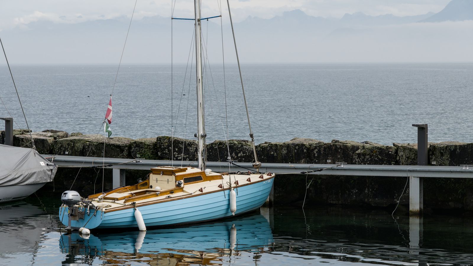 Klassisk segelbåt förtöjd med fendrar vid kajen